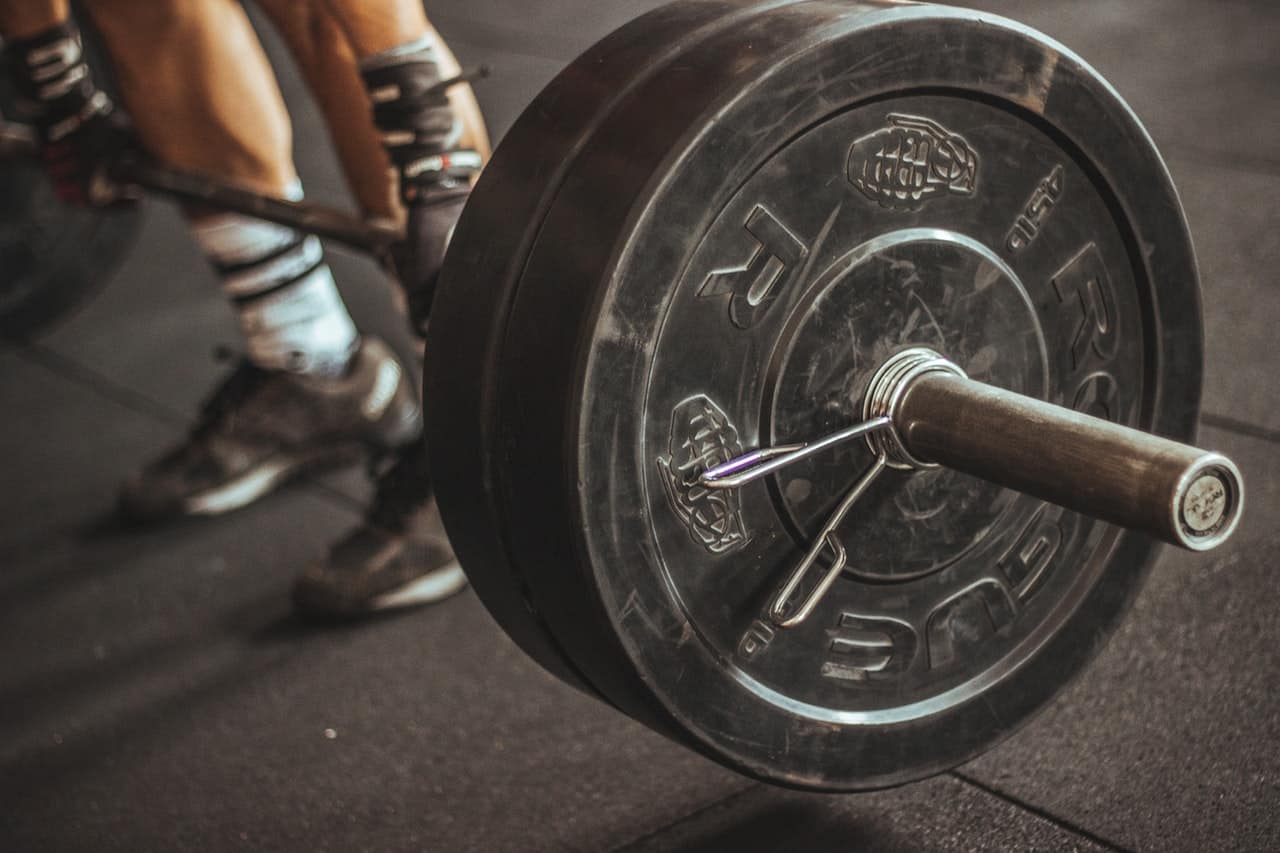 Loaded barbell with black bumper plates on a gym floor